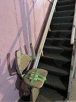 Stair chair lift mounted along staircase, showing seat and rail on stairs with carpet.