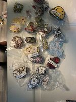 Photo showing multiple individually bagged new animal-themed badges including bears, monkeys, elephants, cows, smiley faces, bunnies and more in cartoon style.
