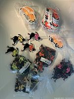 Image showing sealed plastic bags of vintage car badges in orange and red/white colors along with loose and bagged dancing lady badges in multiple colors.