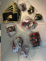 Top-down photo showing playing card badges, Santa face badges, poinsettia badges, and stocking badges in separate piles within plastic bags.
