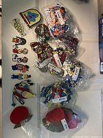 Top-down image of multiple assorted embroidered badges including Sesame Street characters and more, some loose and some packaged in plastic bags.