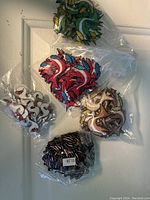 Four sets of fish-shaped badges in assorted colors, individually wrapped in plastic. Colors visible include white with red, red with blue and black, brown with yellow, and green with yellow.
