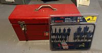 Red toolbox next to Bosch spade bit package on floor.