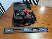 Full kit including Skil XDrive cordless drill within plastic carrying case with charger and battery, alongside aluminum box level lying in front.