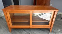 Front view of wooden storage cabinet showing sliding glass doors and overall condition.
