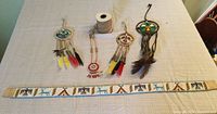 Four Indigenous beadwork dreamcatchers with colorful feathers and one beaded belt laid out on a table.