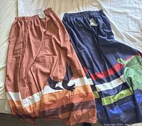 Two silk skirts laid side by side, brown with eagle on left, blue with turtle on right.