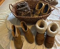 Photo of two pairs of UGG boots, two pairs of mucklucks, all in size 7-8, inside and near a woven basket.