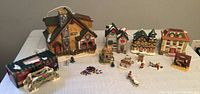 Full collection of Christmas village houses and assorted small figurines displayed on a table.