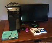 Photo showing Lenovo ThinkCentre desktop tower, BenQ monitor, wired keyboard, wired mouse, wireless purple mouse, unopened Seagate external hard drive, unopened SanDisk solid state drive, and TP-Link AC1300 wireless adapter box all placed on a wooden table.