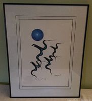 Full front view of the framed Indigenous art "The Long Journey" by Jerry Daniels showing the black and blue serpent-like birds and blue circle with the black metal frame and matting