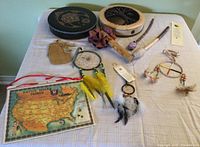 View of entire lot showing two circular drums, dream catchers, leather pouch, Bali nut shaker, mallets, four direction prayer bookmark, and map