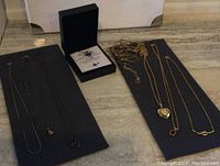 All necklaces displayed on table with black jewelry box containing granddaughter necklace set in the center