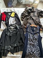 Four women's clothing items laid out on a bed, showing three jackets and one dress.