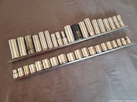Top view of all shallow and long sockets mounted on metal rails, arranged by size.
