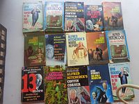 Photo of multiple Alfred Hitchcock hardcover books with illustrated dust jackets laid out on a table