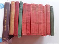 Spine view showing 11 hardcover books with mostly red and green bindings, including titles Perrin's Universal Photography, David Copperfield, and several World's Best Short Stories volumes