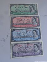 Four Canadian banknotes laid flat, showing the front side with their distinct colors and images of Queen Elizabeth II.
