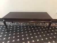 Front and angled view of the solid mahogany coffee table showing smooth top surface and curved legs.