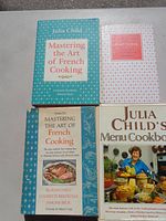 Photo showing four Julia Child cookbooks including Mastering the Art of French Cooking Volume One and Julia Child's Menu Cookbook.