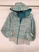 Front view of Lululemon grey and teal striped scuba hoodie showing hood, zipper, and pockets