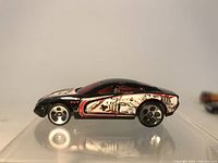 Black Hot Wheels sports car with red and white skeleton-themed side graphic, five-spoke wheels, photographed against white background