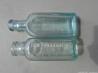 Two small early 1990s tinted light blue glass medicine bottles with embossed text, no chips visible.