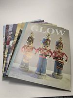 Stacked view of multiple Glow magazines showing three separate cover designs with Christmas collectibles themed imagery.