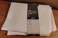 White waffle fabric shower curtain folded with packaging label showing brand 'rth', material type, size and heavy weight collar lining.