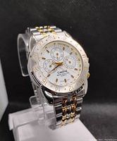 Close-up angled view of the Cardinal watch showing dial with tachymeter bezel, three subdials, gold and silver metal bracelet.