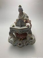 Front view of the porcelain figurine showing the lady in a lace dress seated and playing a piano with floral decorations and gold detailing.