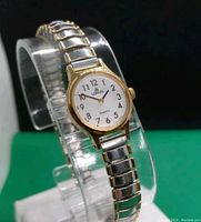 Front view of the Lorus by Seiko women's quartz watch showing white face, black Arabic numerals, gold bezel and two-tone metal expandable band.