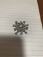 Full front view of the Sherman starburst brooch showing clear rhinestones and silver-tone metal.