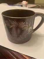 Front and side view of silver plated mug showing floral engravings and 'Xmas' inscription.