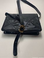 Front view of the vintage black Bally purse showing the strap and buckle closure.