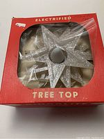 Boxed 5-inch silver electrified tree top star with clear plastic window box showing star inside