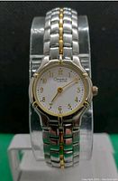 Front-facing close-up of the watch showing the white dial with gold Arabic numerals and gold hands, two-tone metal bracelet with gold accents.