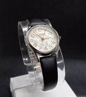 Front angle view showing watch face with gold-tone numerals and black leather strap.