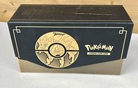 Closed black and gold box with Pokémon Trading Card Game design and Pokémon character artwork.