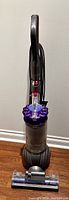 Front view of Dyson upright vacuum cleaner showing main body, handle, power cord, and floor cleaning head.
