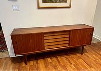 Full front view of the sideboard showing sliding doors, central drawers, and tapered legs