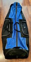 Full view of the blue and black Mizuno travel golf bag laid out flat showing front and handles