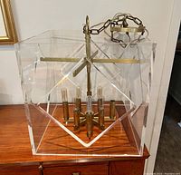 Overall view of square lucite shade suspended by brass chain showing fixture design and components