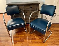 Pair of vintage tubular chrome frame chairs with blue vinyl upholstery seats and backs shown from front angle