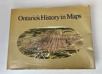 Front of the beige dust jacket showing title 'Ontario's History in Maps' and old aerial map illustration.