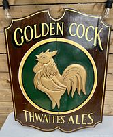 Full front view of the vintage wooden advertising sign featuring a carved golden rooster and bold lettering.