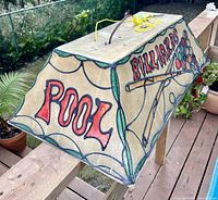 Photo showing the front side with 'POOL' written in large red letters on a beige fibreglass-like shade with green trim details and hanging electrical cord on top.