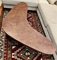 Top angle view of the boomerang shaped coffee table showing the brown mottled laminate top surface and rounded edges.