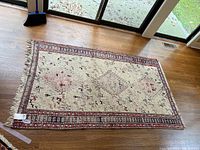 Full view of the woven rectangular area rug laid flat on wood flooring showing its pattern and approximate size.