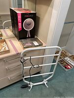 Photo of Evolvico LED beauty mirror in its retail box on a countertop next to a white metal towel warmer frame and jewelry box with jewelry.